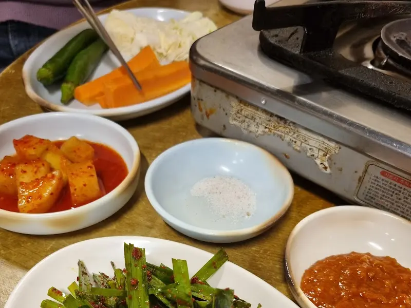 상도곱창 밑반찬. 깍두기, 양념장, 채소 등이 보인다.