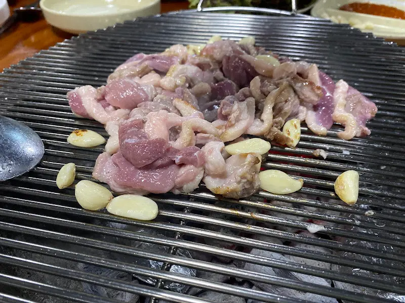 숯불 위에서 노릇노릇 구워지는 오리고기와 마늘