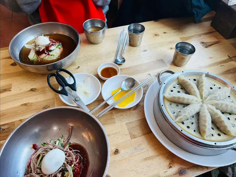 테이블 위에 놓인 물밀면, 비빔밀면, 만두 한 상 차림