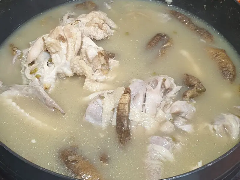 더덕토종닭 근접샷: 뽀얀 국물과 닭고기, 더덕의 조화가 먹음직스러운 모습