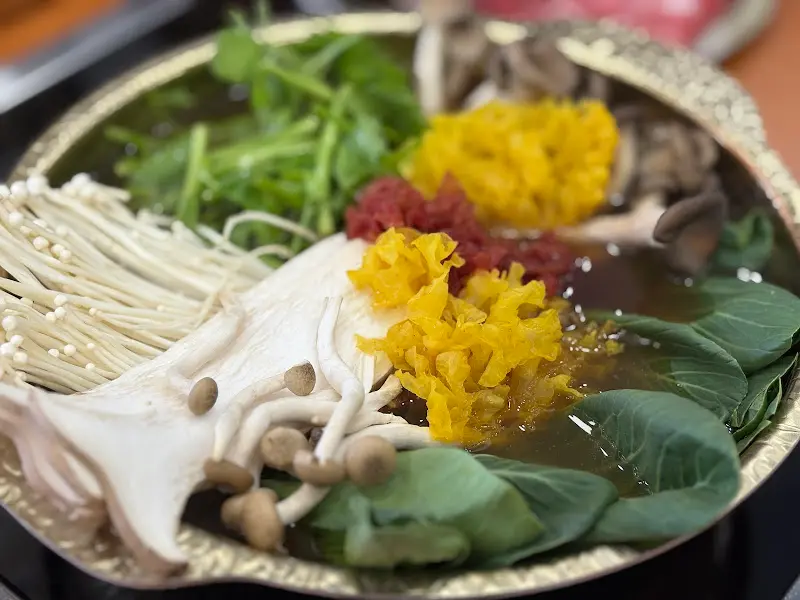 샤브샤브 냄비에 담긴 다채로운 채소와 버섯