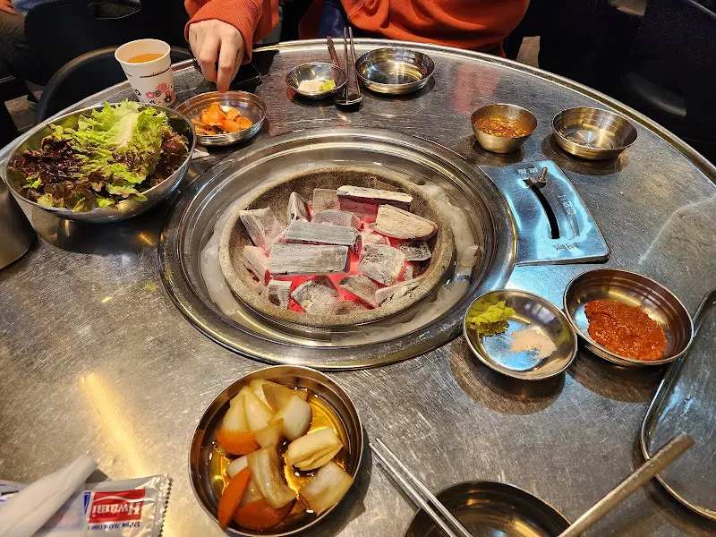 테이블 세팅 모습, 숯불과 다양한 소스, 밑반찬들이 눈에 띈다.