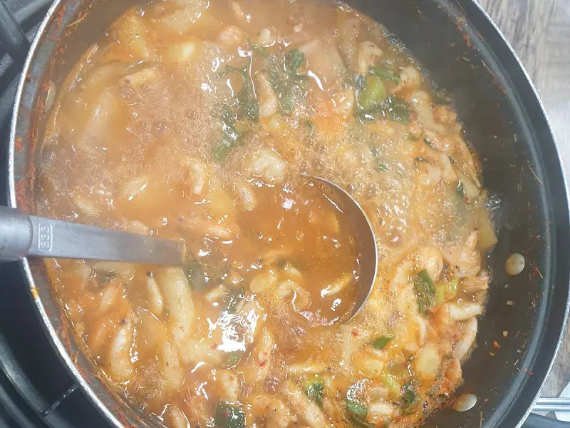 국자로 새뱅이찌개를 뜨는 모습