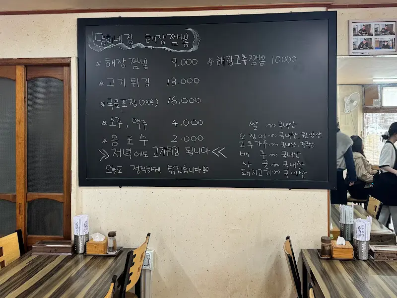 메뉴가 적힌 검은 칠판과 손님들로 가득 찬 가게 내부