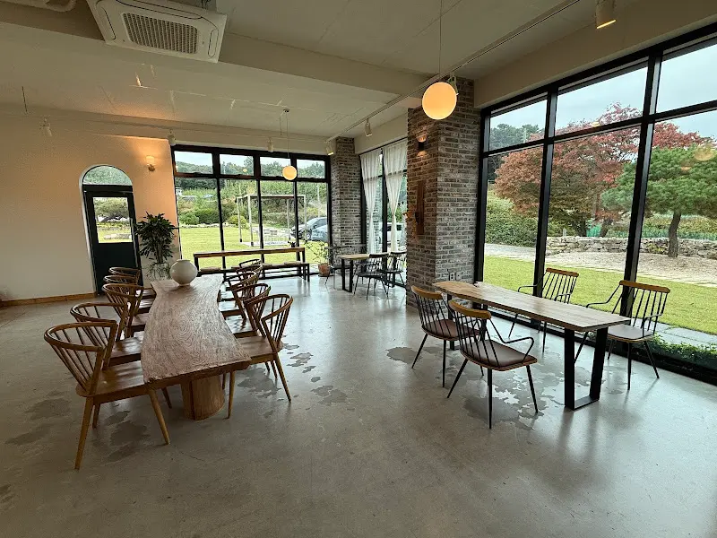 넓은 테이블 간격과 통유리창으로 보이는 풍경이 인상적인 카페 내부