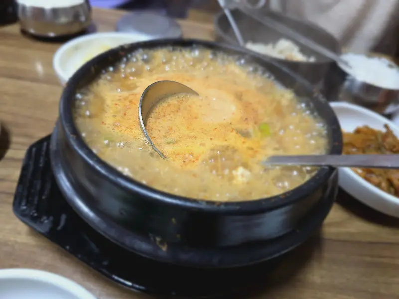 뚝배기 가득 담긴 청국장을 숟가락으로 떠올리는 모습