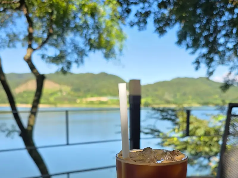 아이스 아메리카노가 놓인 테이블 너머로 호수가 보이는 사진