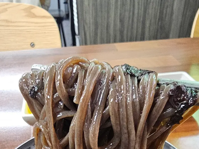 젓가락으로 집어올린 윤기 흐르는 메밀면