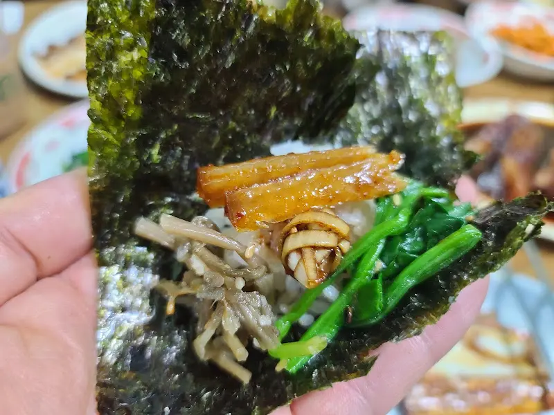 김에 밥과 반찬을 싸서 먹는 모습