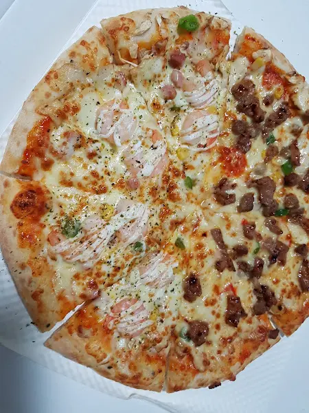 테이블 위에 놓인 피자 한 판. 피자는 이미 여러 조각 잘려져 있으며, 윤기가 흐르는 모습이 먹음직스럽다.