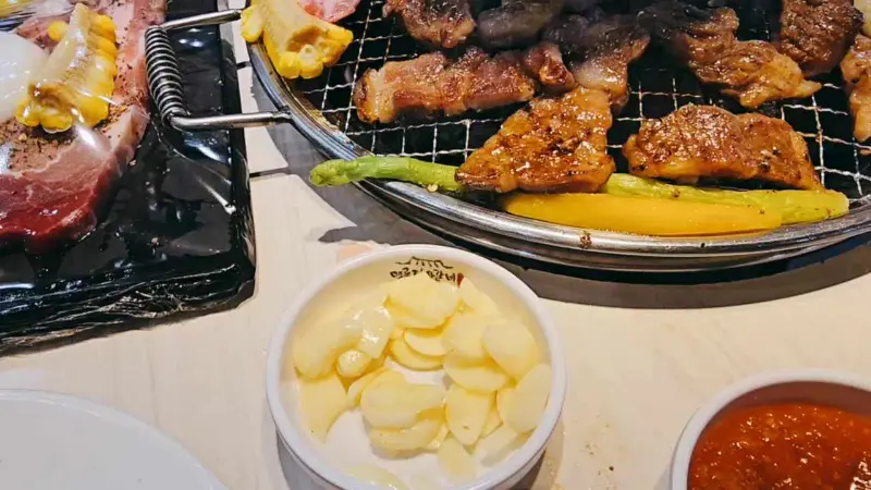 접시에 담긴 마늘과 구워지고 있는 고기