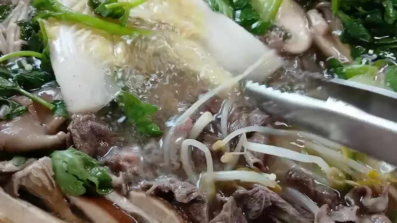 끓고 있는 샤브샤브 육수에 야채와 고기를 넣어 익혀 먹는 모습.