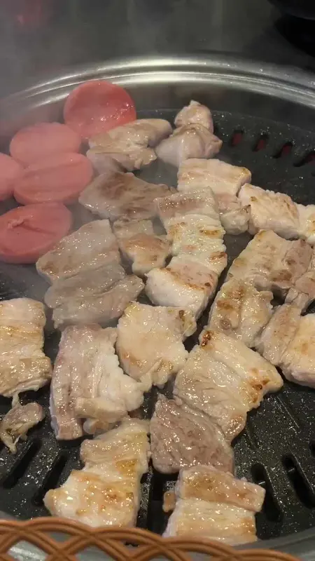 불판 위에서 익어가는 생고기와 분홍 소시지