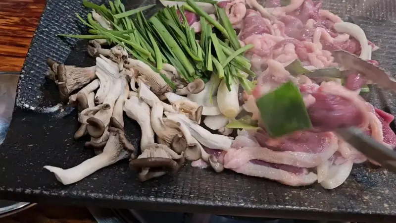 불판 위에서 지글지글 익어가는 오리고기 로스와 채소들