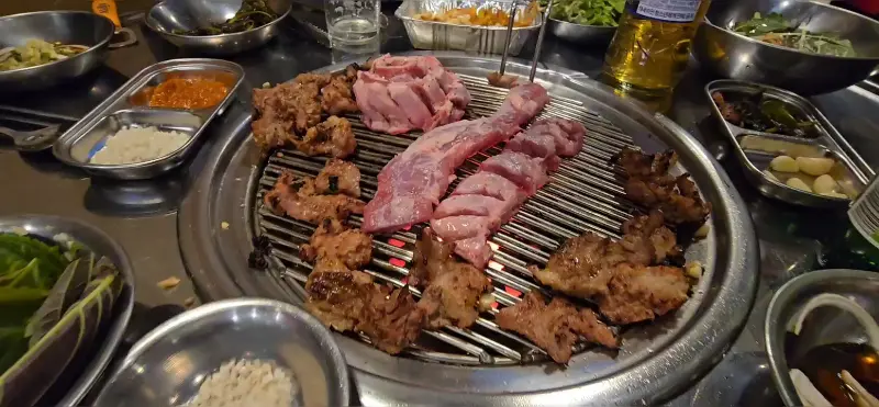 다양한 고기 부위와 풍성한 밑반찬이 한 상 가득 차려진 모습