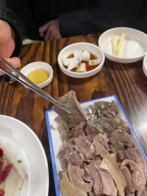 수육을 젓가락으로 집어 올리는 모습