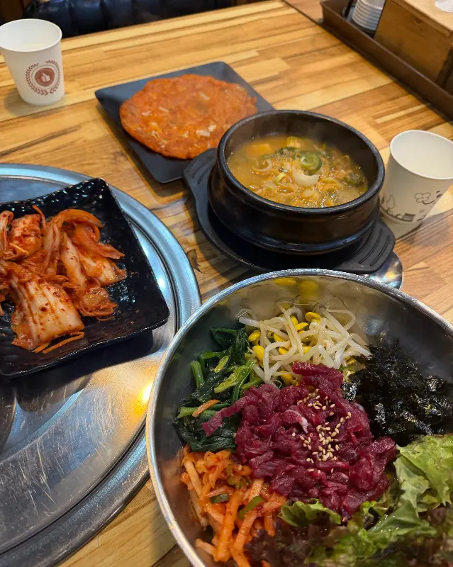 뭉티기와 밑반찬이 함께 놓여있는 테이블 사진