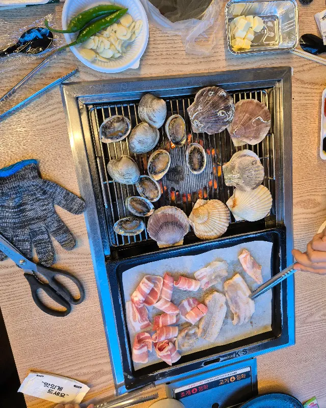 불판 위에서 익어가는 조개와 삼겹살