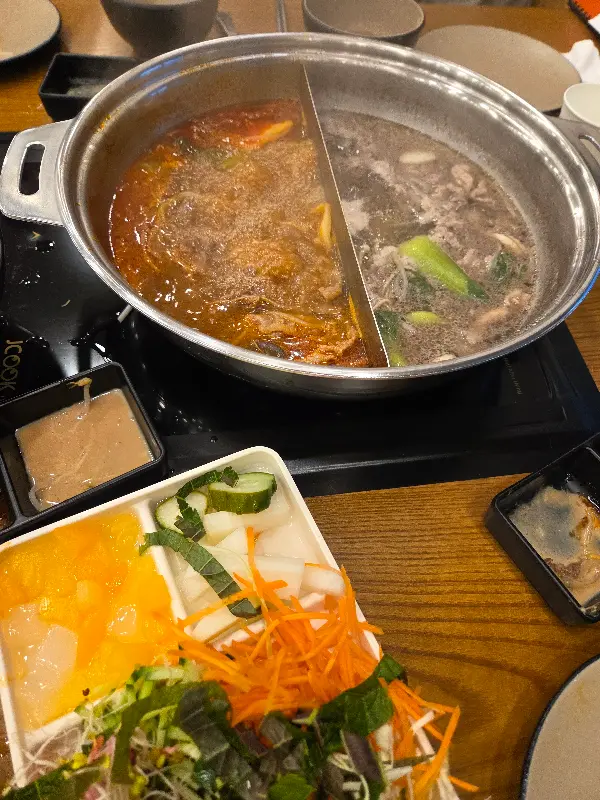 두 가지 육수가 끓고 있는 냄비와 샤브샤브 재료