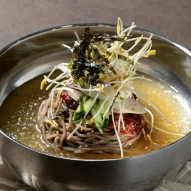 메밀면 위 붉은 양념과 김, 새싹이 조화롭게 올려진 막국수