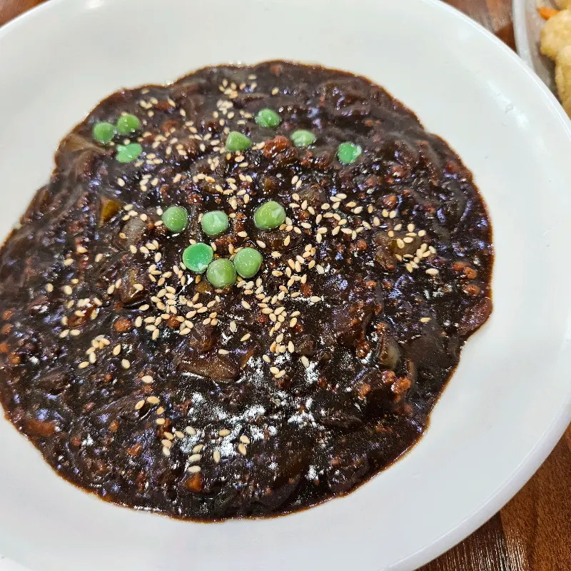 짜장면 위에 뿌려진 깨와 완두콩