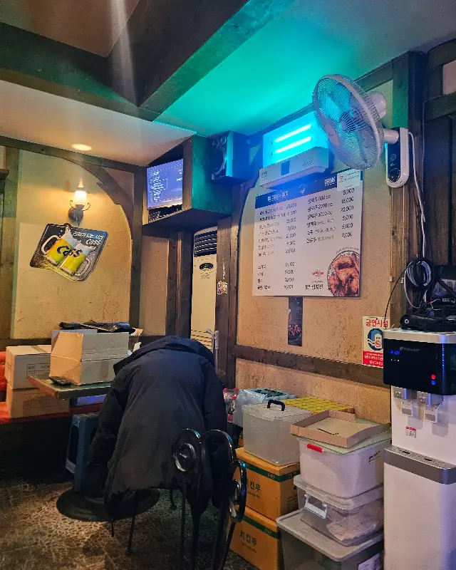 실내 사진. 테이블과 의자가 놓여 있고, 벽에는 메뉴판과 장식물이 걸려 있다.