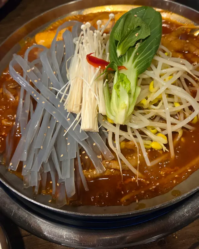 93불고기오징어전골에 넓적당면, 콩나물, 떡, 채소가 푸짐하게 들어간 모습