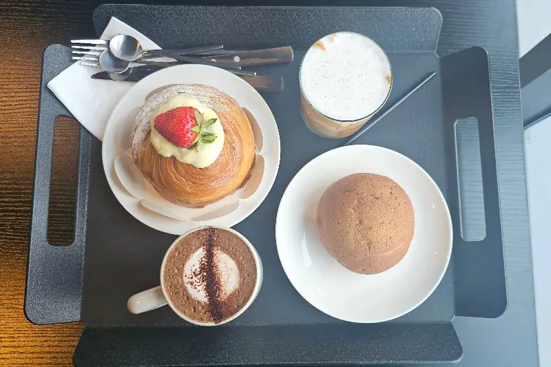 테이블 위에 놓인 음료와 빵. 남마에이드, 창녕 양파빵, 로얄 캐모마일이 보인다.