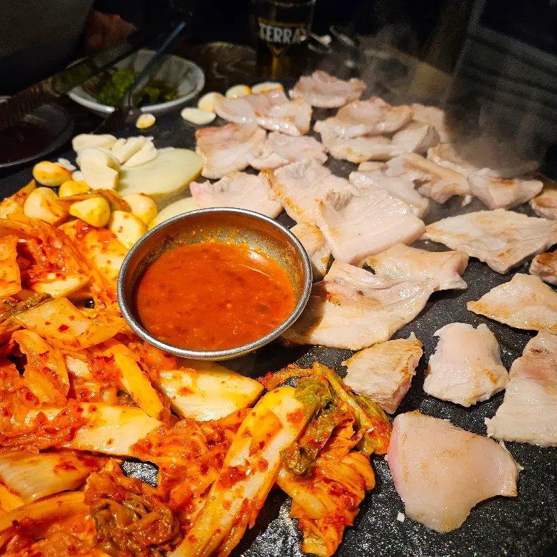 돌판 위에 김치, 마늘, 고기가 함께 구워지는 모습