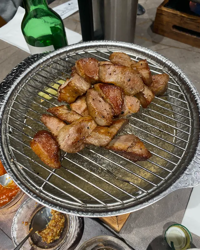 구워져 나온 삼겹살이 석쇠 위에 올려져 있다.