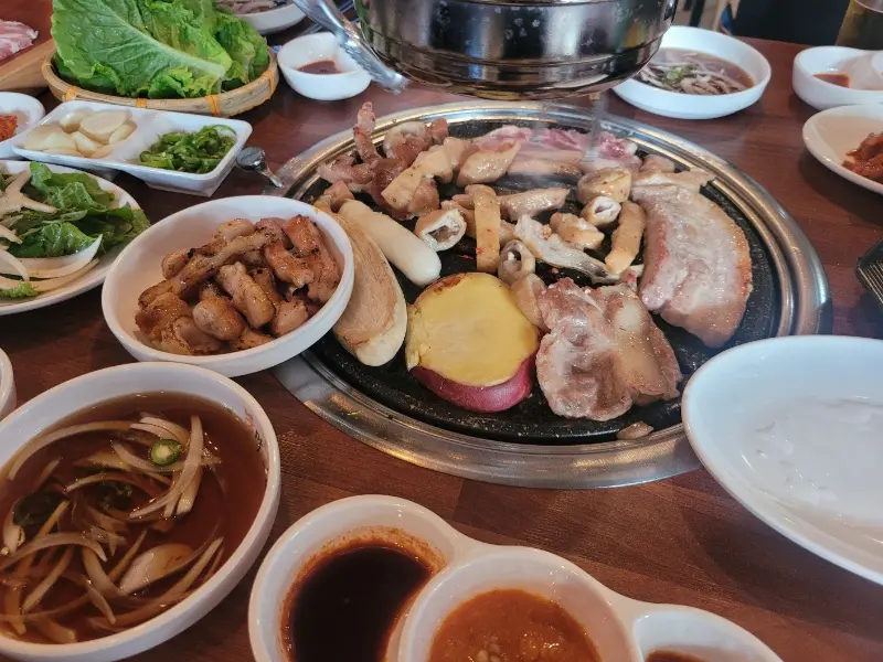 불판 위에서 막창, 삼겹살, 팽이버섯이 함께 구워지는 모습