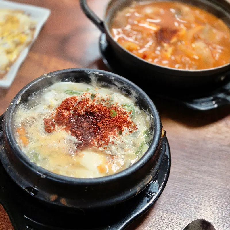순두부찌개와 김치찌개가 테이블 위에 놓여 있는 사진