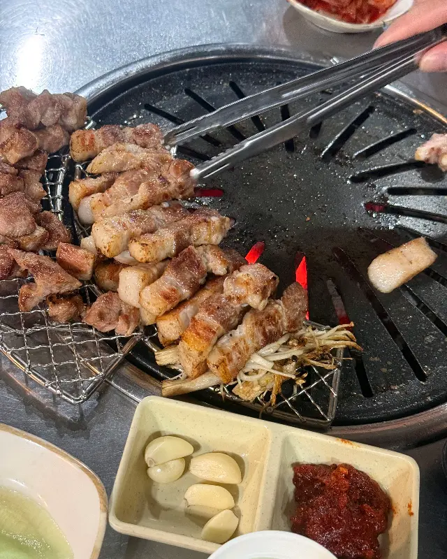 숯불 위에서 익어가는 삼겹살과 김치, 마늘