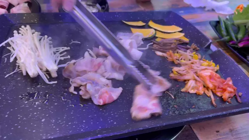 대패삼겹살과 김치, 콩나물, 버섯을 함께 구워 먹는 모습