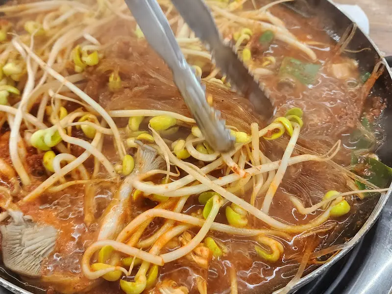 끓고 있는 물갈비 안의 콩나물과 당면을 집게로 들어올리는 모습