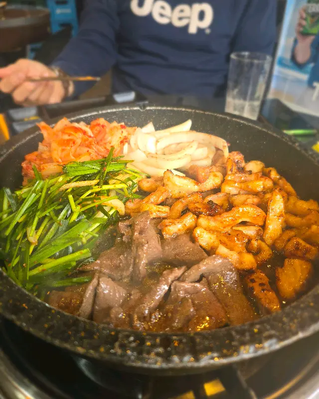 불판 위에 곱창, 김치, 부추, 양파가 함께 구워지는 모습
