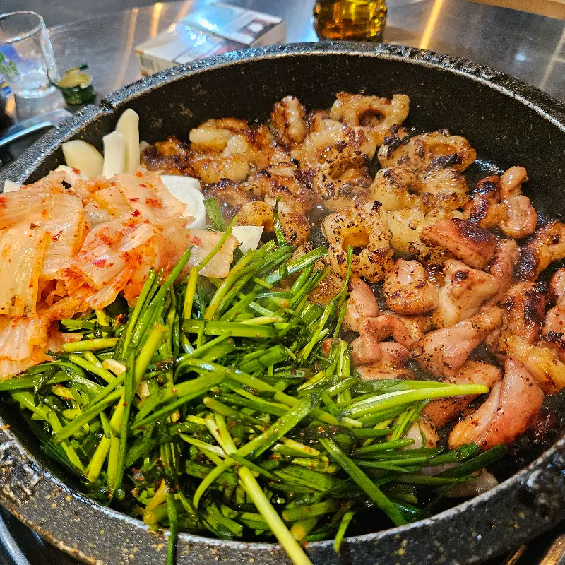 불판 위에 곱창, 막창, 김치, 부추가 함께 구워지는 모습