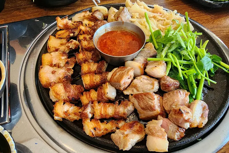 잘 구워진 삼겹살과 미나리가 함께 담겨 먹음직스러운 모습