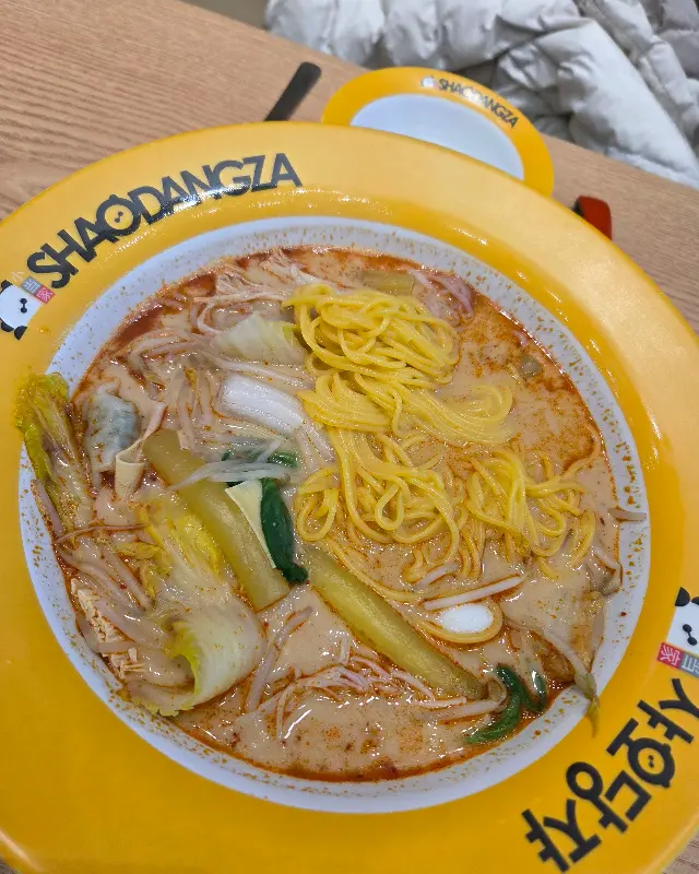 노란색 그릇에 담긴 마라탕. 면과 채소가 주를 이루고 있다.