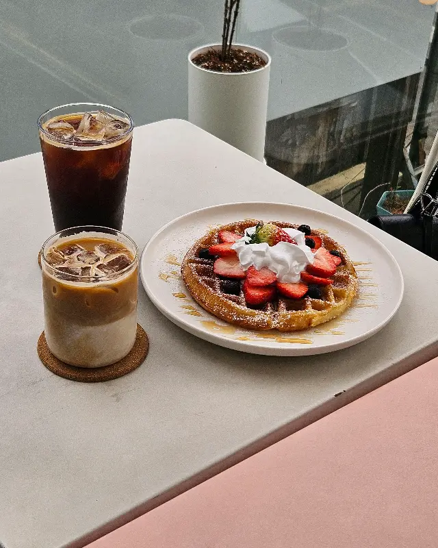 테이블 위에 놓인 딸기 와플과 음료