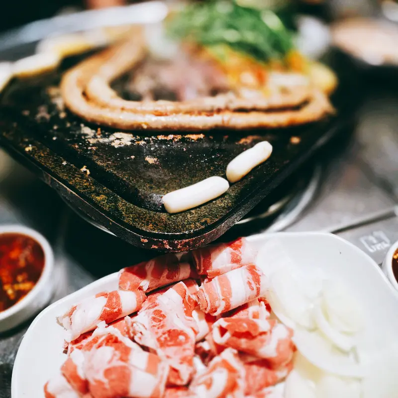 돌판 위에 구워진 대창과 함께 놓여 있는 우삼겹 접시