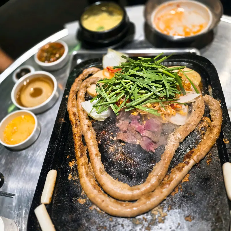 돌판 위에 길게 늘어진 대창과 가운데 쌓인 부추, 양파 등의 모습