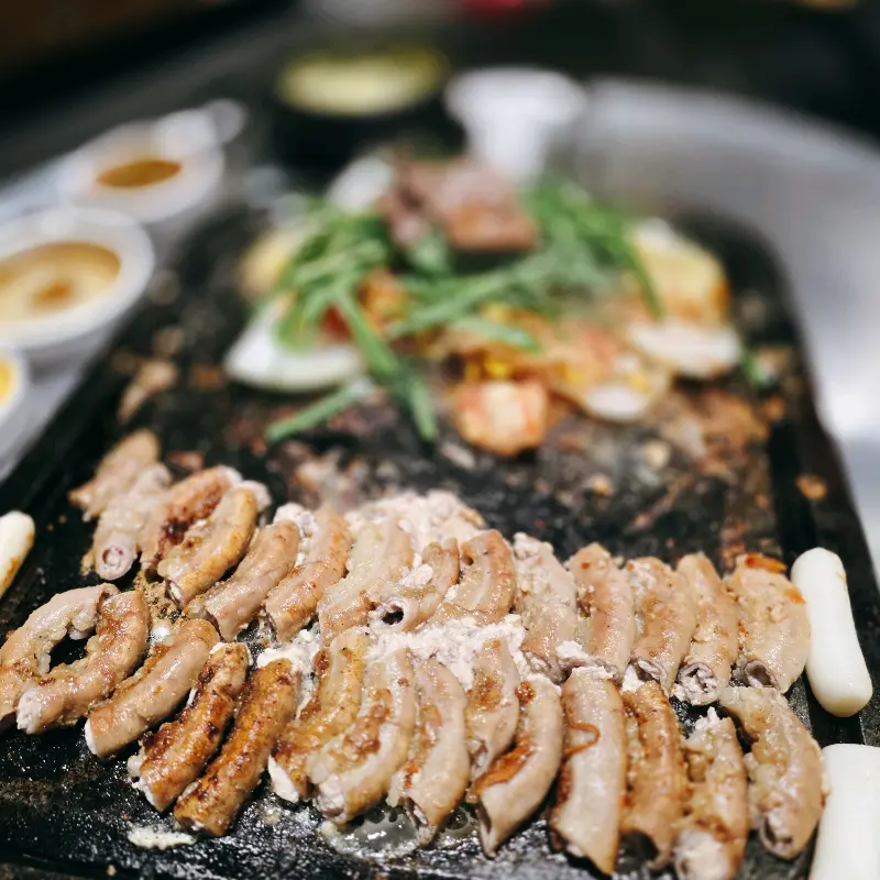 돌판 위에 곱창, 대창, 염통, 떡, 김치 등이 가지런히 놓여 있는 모습