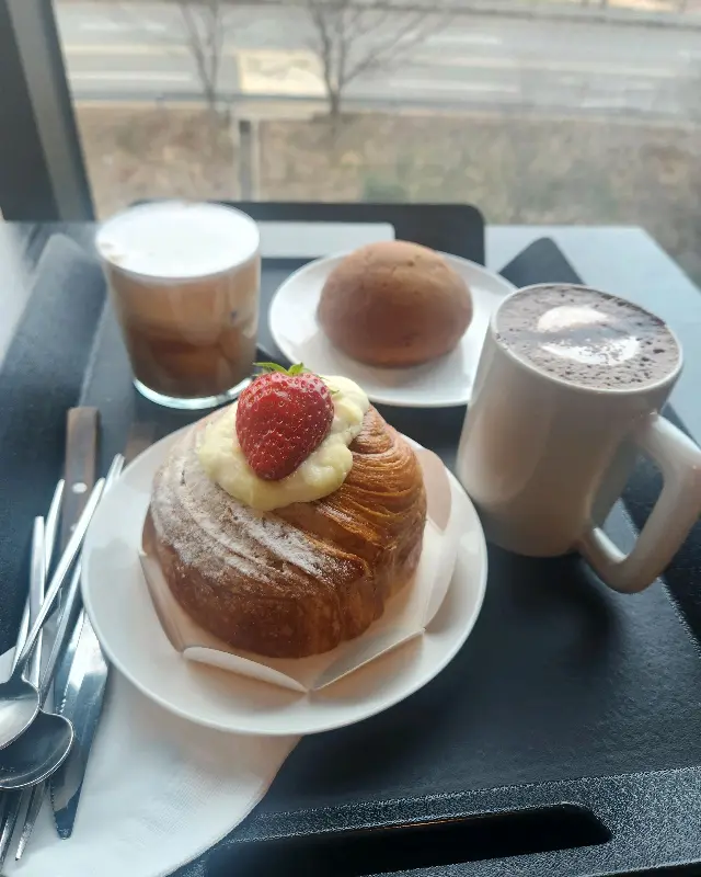 테이블 위에 놓인 음료와 빵. 남마에이드, 창녕 양파빵, 로얄 캐모마일이 보인다.