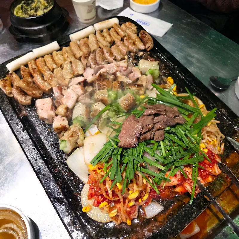 돌판 위에 다양한 종류의 곱창, 막창, 대창, 염통과 야채가 푸짐하게 놓여 있는 모습