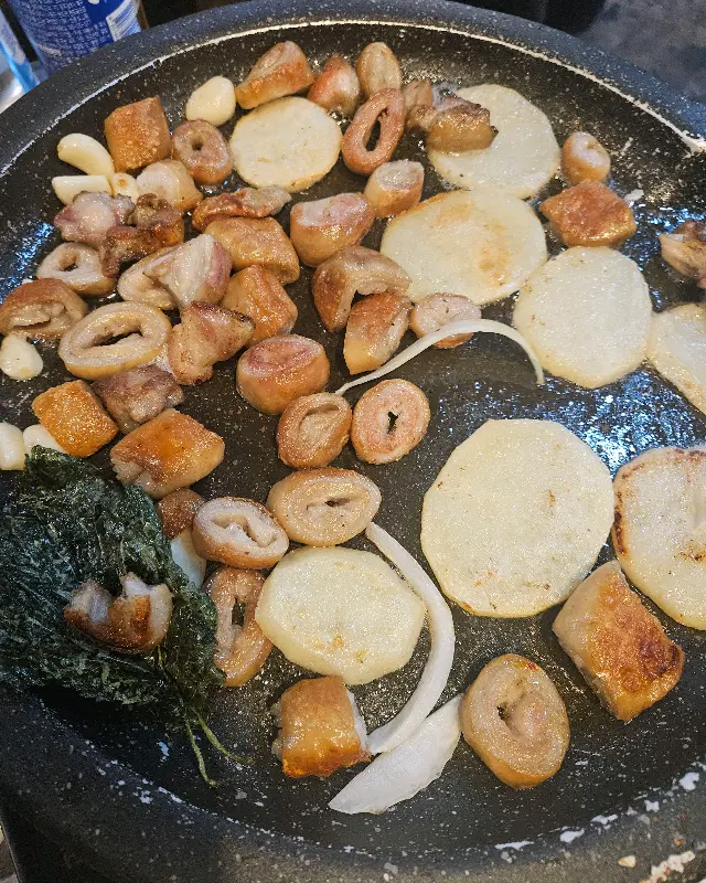 불판 위에 막창, 감자, 마늘이 함께 구워지는 모습