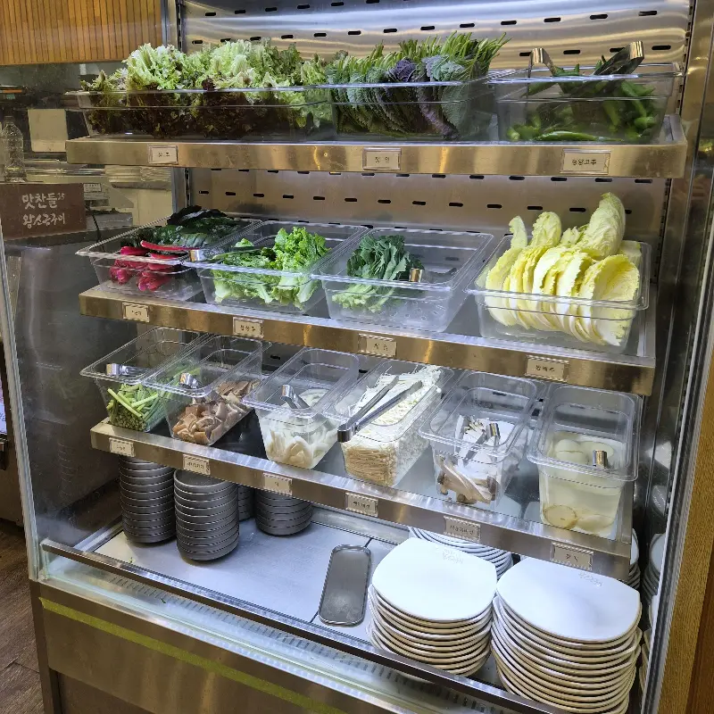 신선한 채소와 다양한 곁들임 재료들이 가지런히 진열된 셀프바의 모습