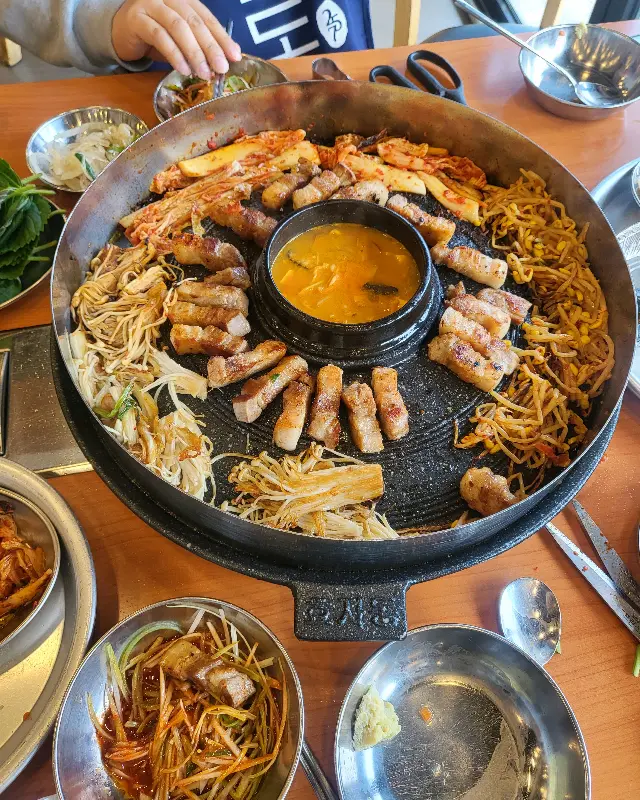 솥뚜껑 가득 채워진 삼겹살과 곁들임