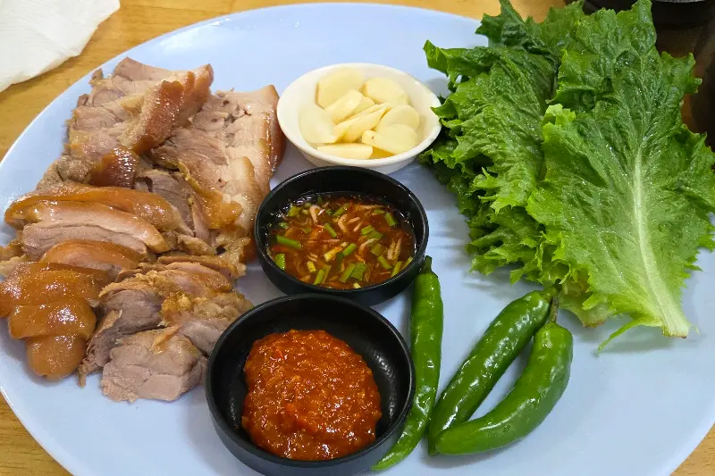 윤기가 흐르는 수육과 신선한 쌈 채소