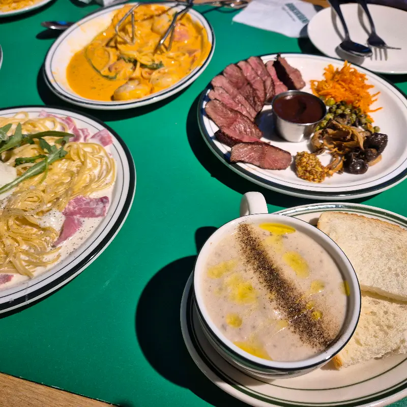 스테이크, 파스타, 스프 등 다양한 메뉴가 테이블 위에 놓여있는 모습